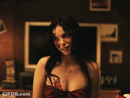 A Woman With Blood On Her Face Is Standing In Front Of A Tv GIF