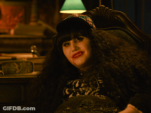 A Woman With Blood On Her Face Is Wearing A Hat And Making A Rock Sign GIF