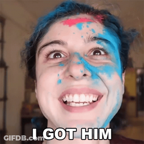 A Woman With Blue And Pink Paint On Her Face Smiles And Says " I Got Him " GIF