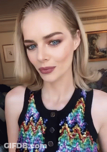 A Woman With Blue Eyes Is Wearing A Sequined Top With Buttons GIF