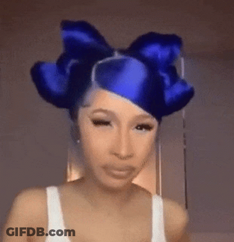 A Woman With Blue Hair And A Blue Bow In Her Hair Is Making A Funny Face . GIF