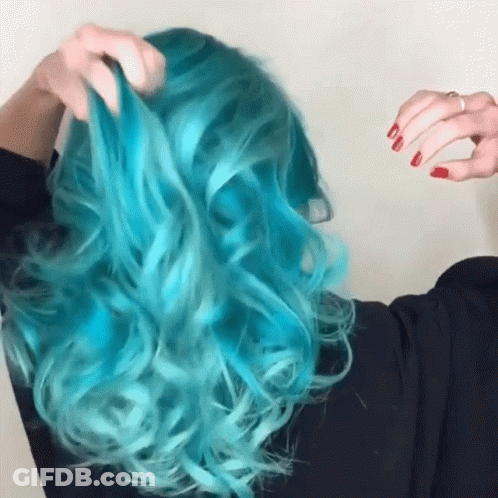 A Woman With Blue Hair And Red Nails Is Holding Her Hair GIF