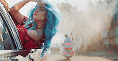 A Woman With Blue Hair Is Sitting In A Car Looking Out The Window GIF