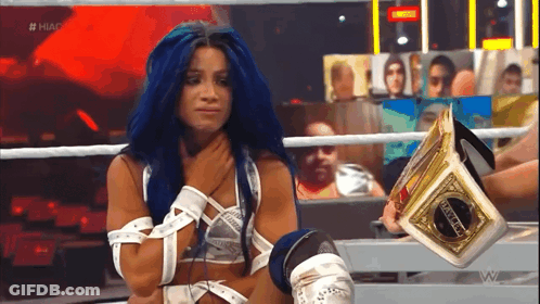 A Woman With Blue Hair Is Sitting In A Ring Holding A Championship Belt . GIF
