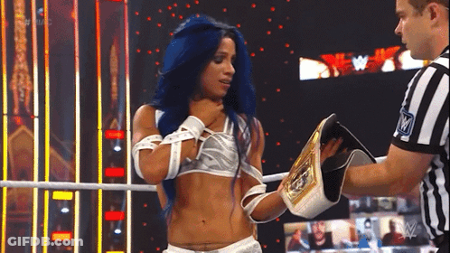 A Woman With Blue Hair Is Standing In A Wrestling Ring Holding A Championship Belt And Talking To A Referee . GIF