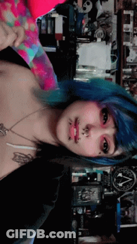 A Woman With Blue Hair Is Standing In Front Of A Sign That Says ' Apocalypse ' GIF