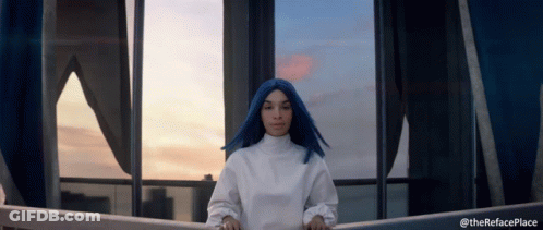 A Woman With Blue Hair Is Standing In Front Of A Window With The Words " Therefaceplace " Below Her GIF