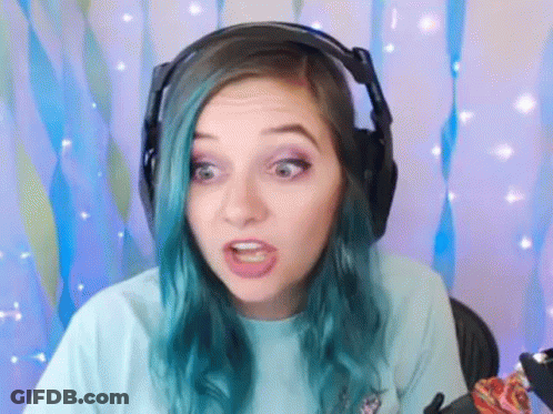 A Woman With Blue Hair Is Wearing Headphones And Making A Face . GIF