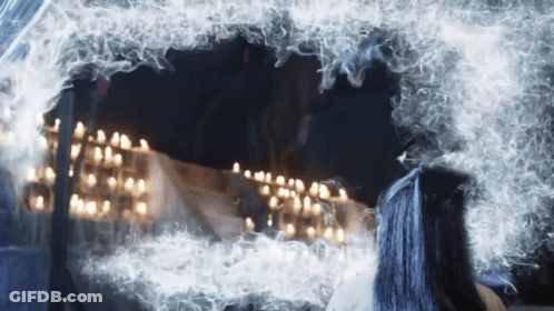 A Woman With Blue Hair Looks At Herself In A Mirror GIF