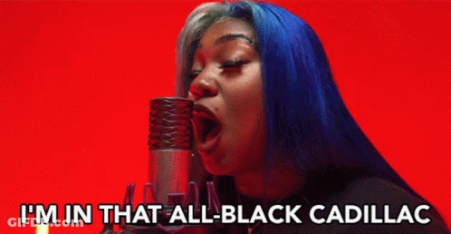 A Woman With Blue Hair Singing Into A Microphone With The Words I 'M In That All Black Cadillac Below Her GIF
