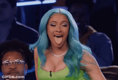 A Woman With Blue Hair Sticking Her Tongue Out While Wearing A Green Top GIF