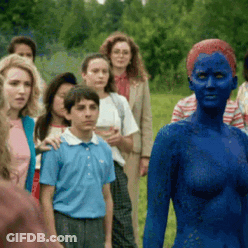 A Woman With Blue Paint On Her Face Stands In Front Of A Crowd GIF