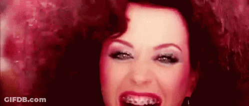 A Woman With Braces On Her Teeth Is Smiling And Looking At The Camera . GIF