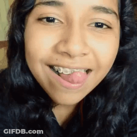 A Woman With Braces On Her Teeth Is Sticking Her Tongue Out GIF