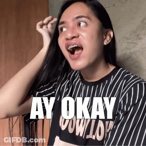 A Woman With Braces On Her Teeth Is Wearing A Black And White Striped Shirt That Says Ay Okay GIF