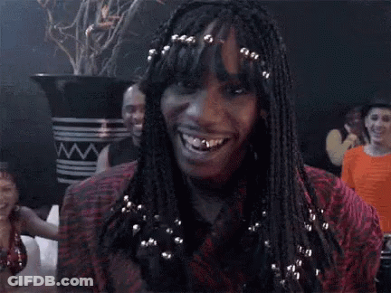 A Woman With Braids And A Ring On Her Finger Is Smiling And Making A Funny Face . GIF