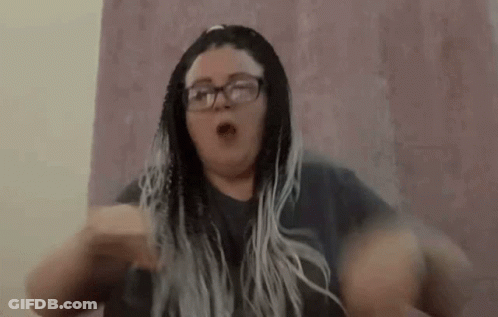 A Woman With Braids And Glasses Is Making A Funny Face With Her Hands In The Air . GIF