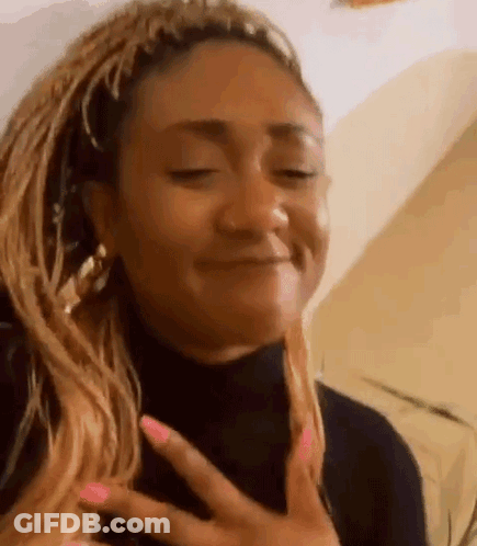 A Woman With Braids And Pink Nails Is Making A Funny Face . GIF