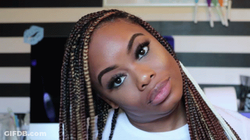 A Woman With Braids Is Looking At The Camera With A Striped Wall In The Background GIF