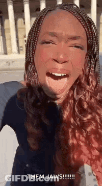 A Woman With Braids Is Making A Funny Face With Her Tongue Hanging Out . GIF