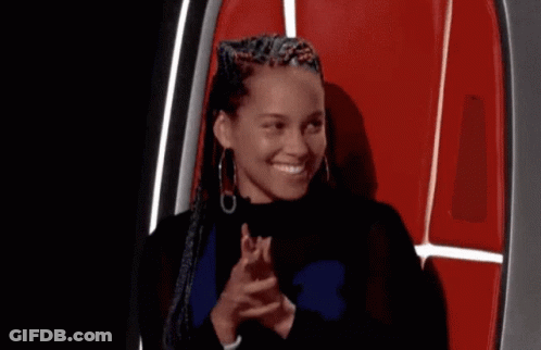 A Woman With Braids Is Sitting In A Chair Covering Her Mouth With Her Hand . GIF