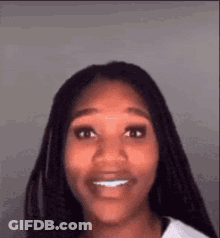 A Woman With Braids Is Smiling For The Camera . GIF