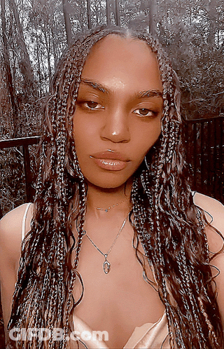 A Woman With Braids Is Wearing A Necklace With A Heart Pendant GIF