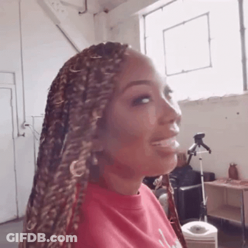 Woman With Braids Smiling In Front Of Window GIF