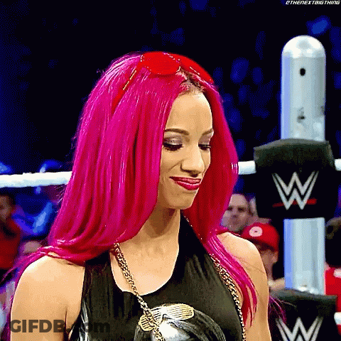 A Woman With Bright Pink Hair Is Standing In A Wrestling Ring Wearing Sunglasses . GIF
