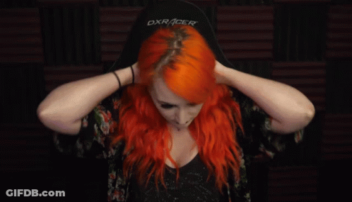 A Woman With Bright Red Hair Is Holding Her Hair In Her Hands . GIF