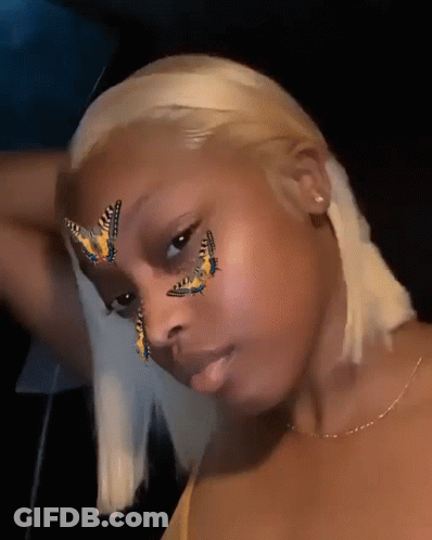 A Woman With Butterflies Painted On Her Face Looks At The Camera GIF