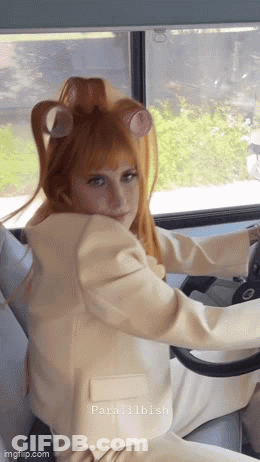 A Woman With Curlers In Her Hair Is Driving A Car GIF