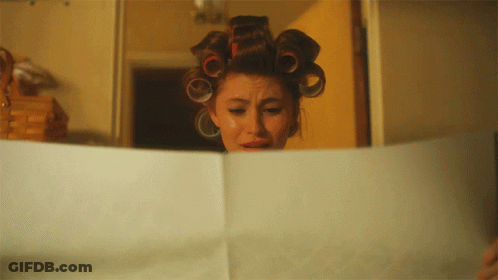 A Woman With Curlers On Her Head Is Reading A Piece Of Paper GIF