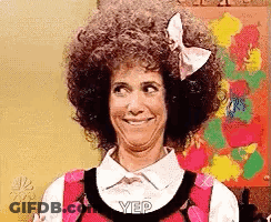 A Woman With Curly Hair And A Bow On Her Head Is Smiling And Making A Funny Face . GIF