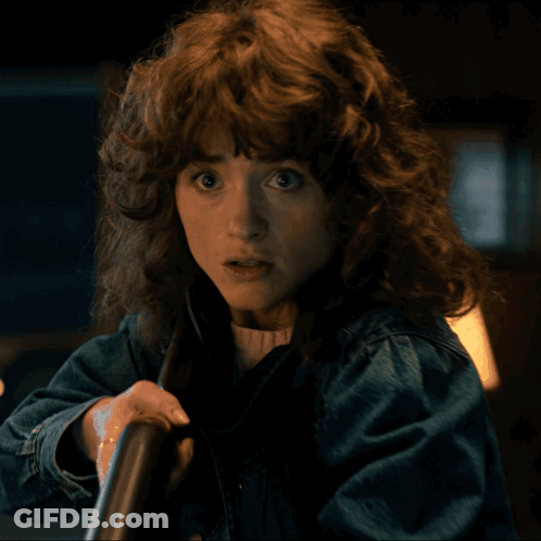A Woman With Curly Hair And A Denim Jacket GIF