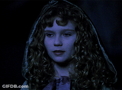 A Woman With Curly Hair And A Hood On Her Head Looks At The Camera GIF