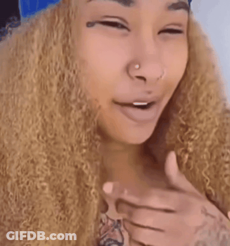 A Woman With Curly Hair And A Tattoo On Her Hand GIF