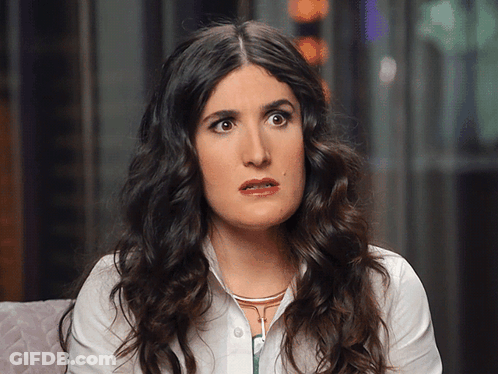 A Woman With Curly Hair And A White Shirt Looks Surprised GIF