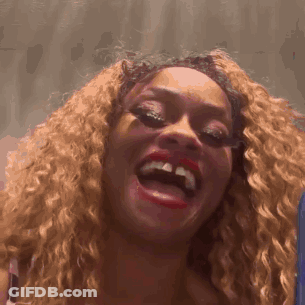 A Woman With Curly Hair And Red Lips Is Laughing GIF