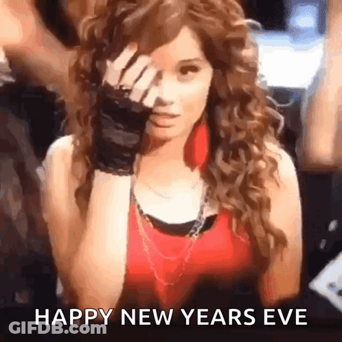 A Woman With Curly Hair Is Covering Her Face With Her Hand And The Words Happy New Years Eve Are Written Below Her GIF