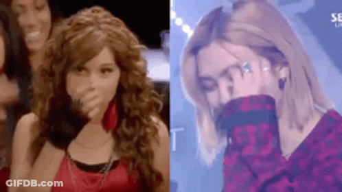 A Woman With Curly Hair Is Covering Her Mouth With Her Hand And A Woman With Blonde Hair Is Covering Her Face With Her H GIF