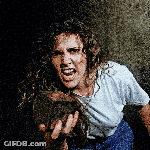 A Woman With Curly Hair Is Holding A Rock In Her Hands GIF