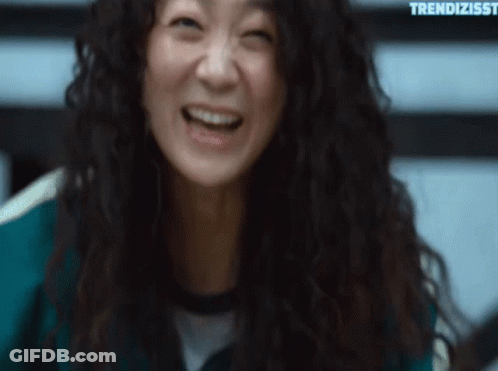 A Woman With Curly Hair Is Laughing And Making A Funny Face . GIF