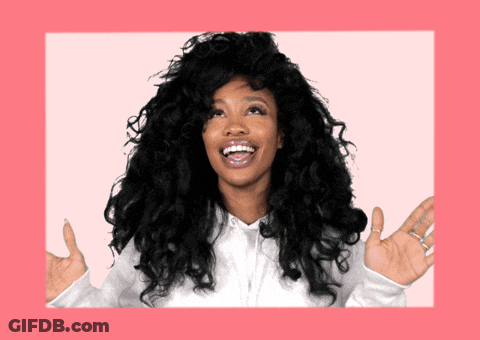 A Woman With Curly Hair Is Laughing With Her Hands Outstretched In Front Of A Pink Background GIF