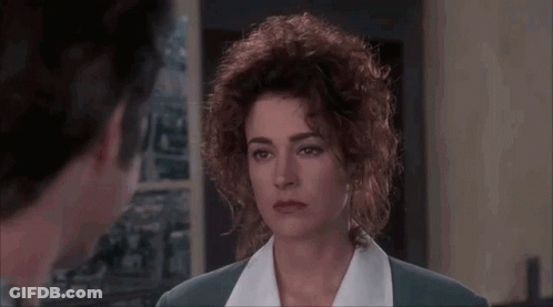 A Woman With Curly Hair Is Looking At A Man In A Room In A Movie . GIF
