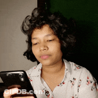 A Woman With Curly Hair Is Looking At Her Phone . GIF