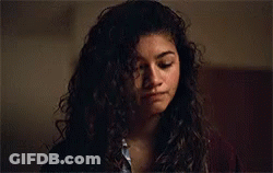 A Woman With Curly Hair Is Looking Down At Something GIF