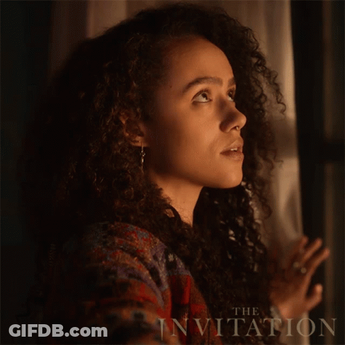A Woman With Curly Hair Is Looking Out A Window With The Words The Invitation Behind Her GIF
