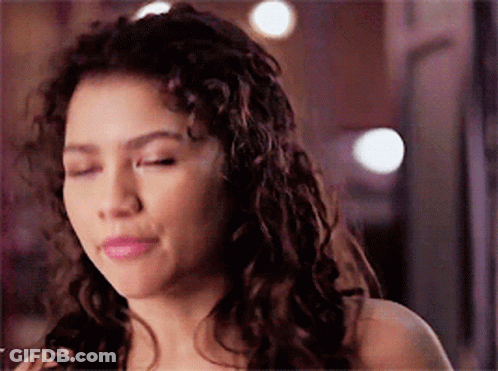 A Woman With Curly Hair Is Making A Funny Face GIF