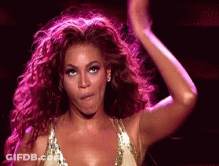 A Woman With Curly Hair Is Making A Funny Face And Dancing On A Stage . GIF